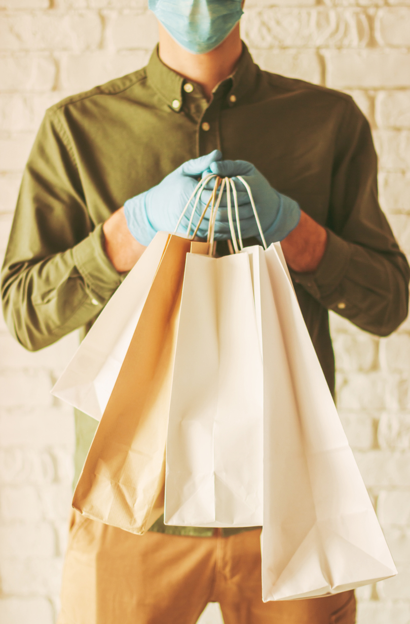 Delivery guy courier holding shopping bags in hands